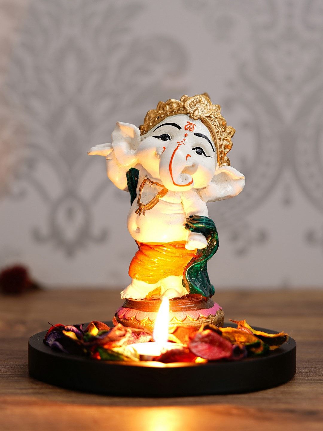 eCraftIndia Off-White & Orange Lord Ganesha Dancing Avatar Showpiece With Wooden Base, Petals & Tealight Price in India