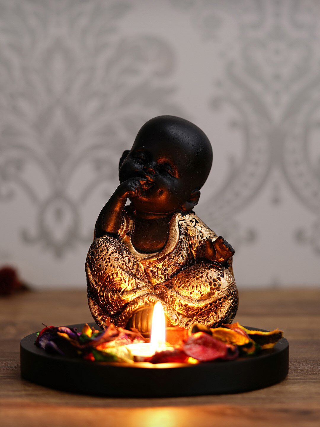 eCraftIndia Black & Gold Handcrafted Smiling Monk Buddha with Wooden Base, Fragranced Petals and Tealight Price in India