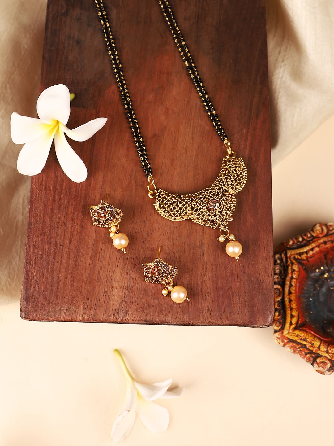 ANIKAS CREATION Gold-Plated Black & Beige Stone-Studded & Beaded Mangalsutra With Earrings
ANIKAS CREATION Gold-Plated Black & Beige Stone-Studded & Beaded Mangalsutra With Earrings