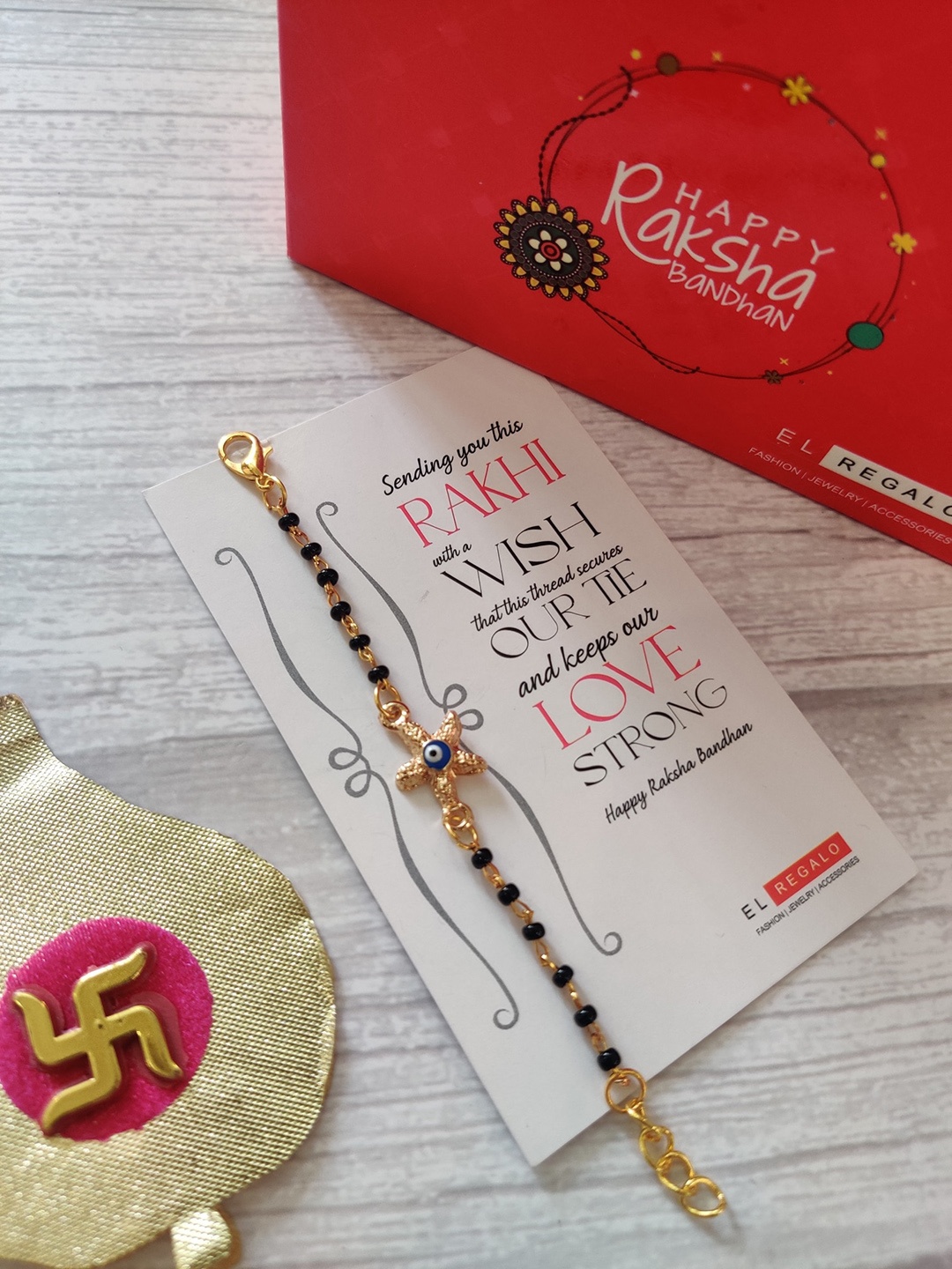 EL REGALO Kids Gold-Toned Nazaria Rakhi Combo with Greeting Card & Roli Chawal Shagun
EL REGALO Kids Gold-Toned Nazaria Rakhi Combo with Greeting Card & Roli Chawal Shagun