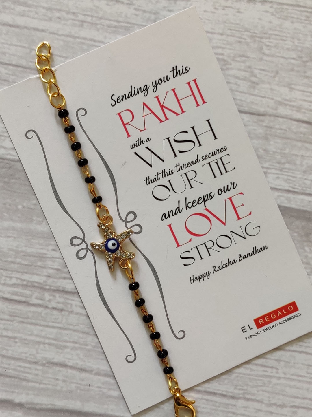 EL REGALO Kids Gold-Toned Nazaria Rakhi Combo with Greeting Card & Roli Chawal Shagun
EL REGALO Kids Gold-Toned Nazaria Rakhi Combo with Greeting Card & Roli Chawal Shagun