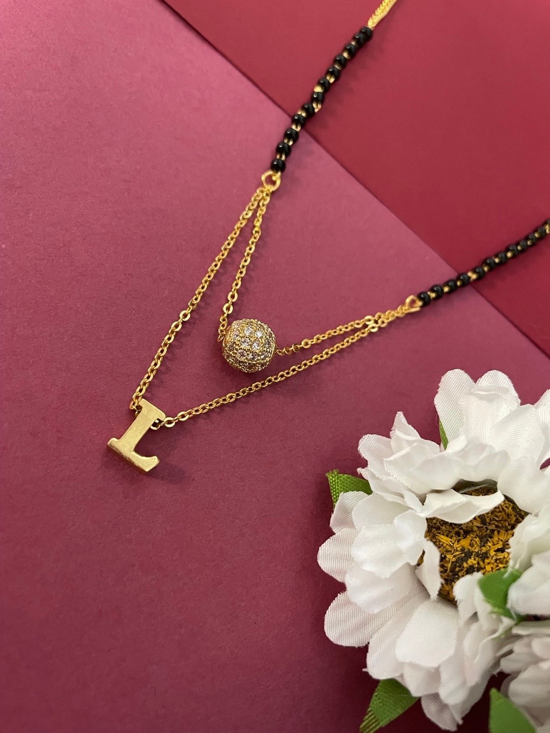Digital Dress Room Gold-Plated L Letter Shaped AD Stone-Studded Ball & Beaded Mangalsutra
Digital Dress Room Gold-Plated L Letter Shaped AD Stone-Studded Ball & Beaded Mangalsutra