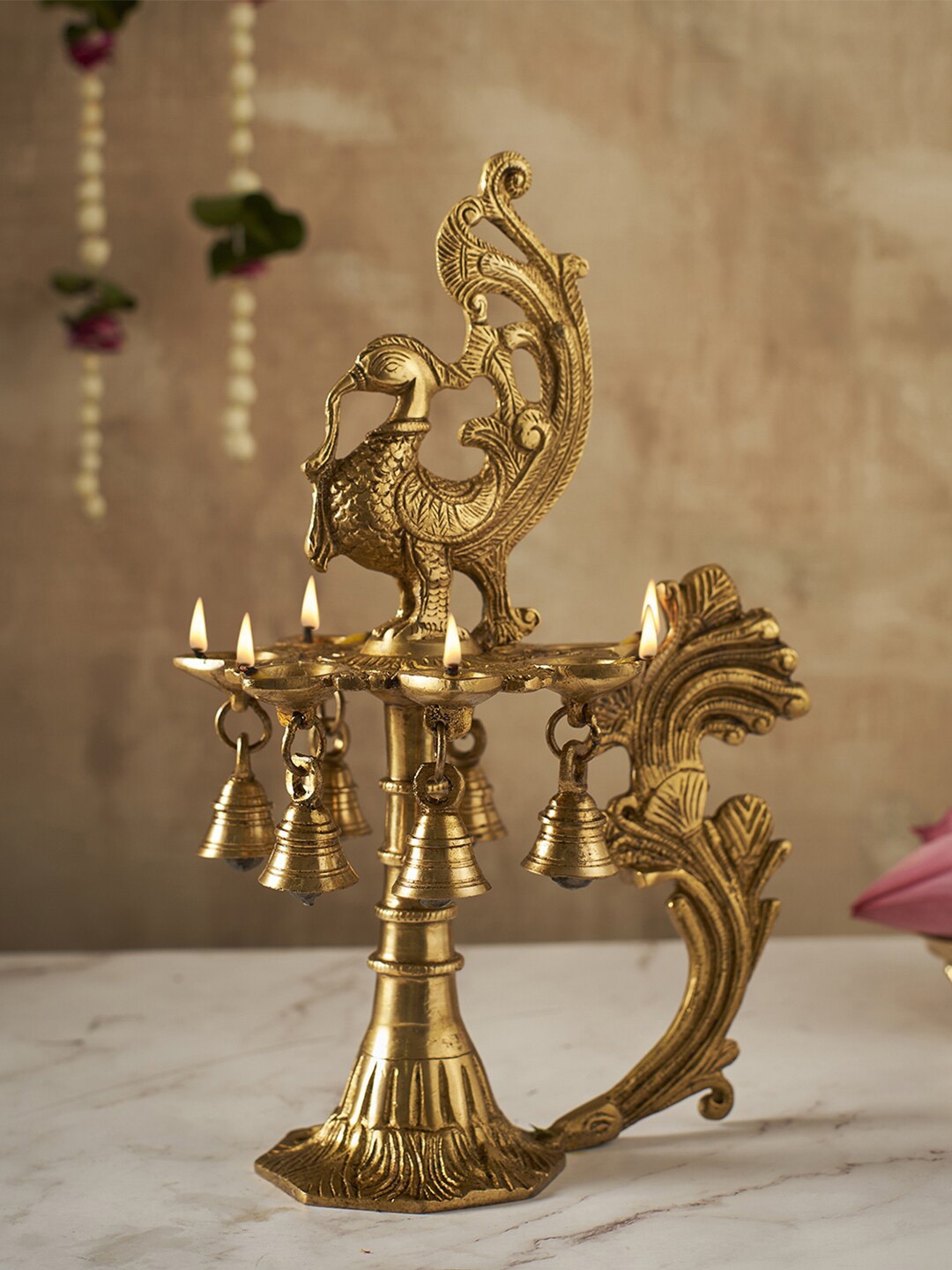 DecorTwist Gold-Toned Elegant Brass 7-Face Diya with Antique Finish and Hanging Bells
DecorTwist Gold-Toned Elegant Brass 7-Face Diya with Antique Finish and Hanging Bells