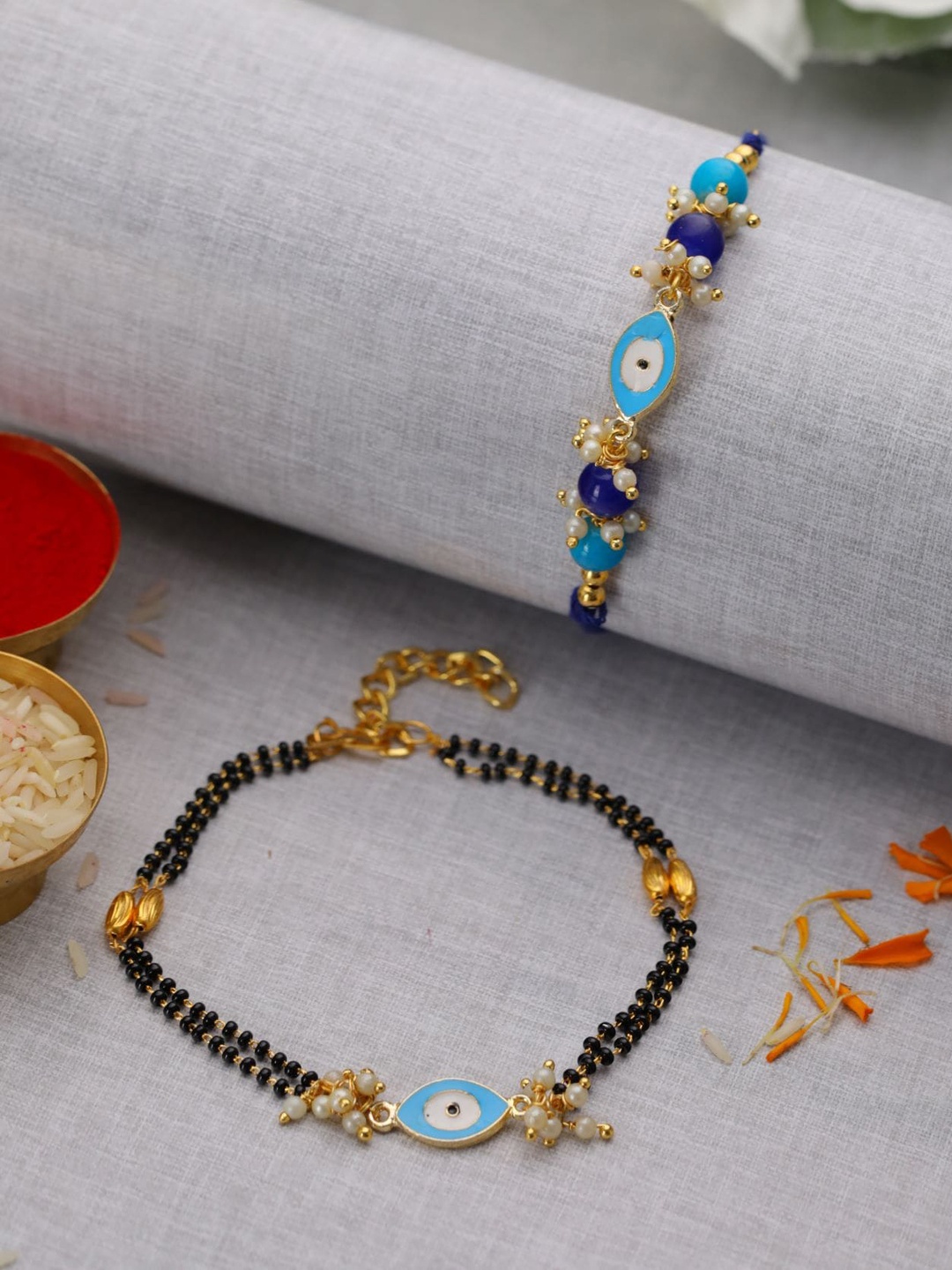 Jazz and Sizzle Set Of 2 Evil Eye & Pearl Beaded Bhaiya Bhabhi Rakhi With Roli & Chawal, Blue
Jazz and Sizzle Set Of 2 Evil Eye & Pearl Beaded Bhaiya Bhabhi Rakhi With Roli & Chawal, Blue