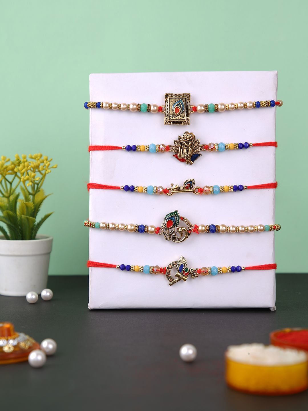 Aapno Rajasthan Set Of 5 Krishna & Peacock Feather Beaded Rakhis With Roli Chawal, Red
Aapno Rajasthan Set Of 5 Krishna & Peacock Feather Beaded Rakhis With Roli Chawal, Red