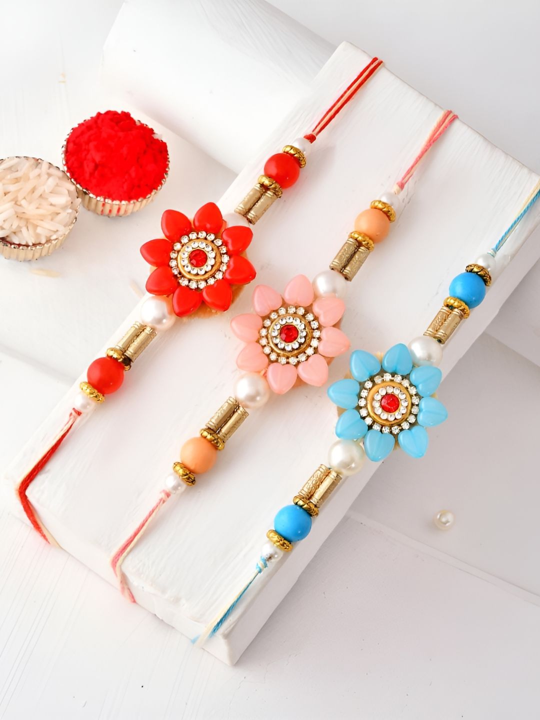 Myntra Elegant Homes Set Of 3 Floral Thread Rakhis With Greeting Card & Roli Chawal-image-29