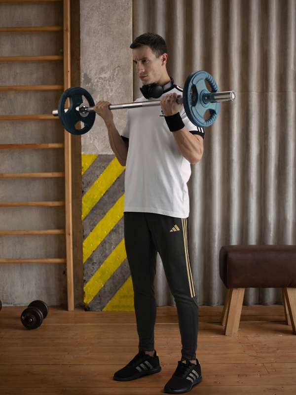 Premium Photo  Young woman in green sports bra and black pants doing  exercises with red barbell on black bricks background