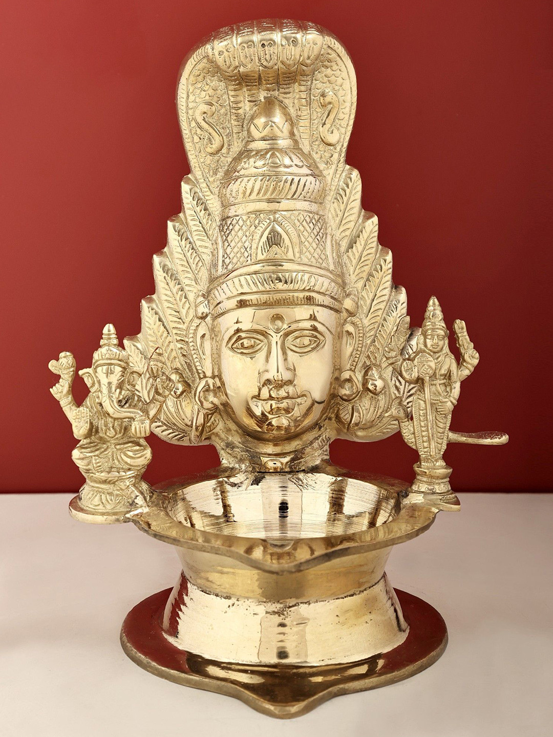 Exotic India Gold Toned Textured Brass Parvati Diya with Ganesha and Karttikeya