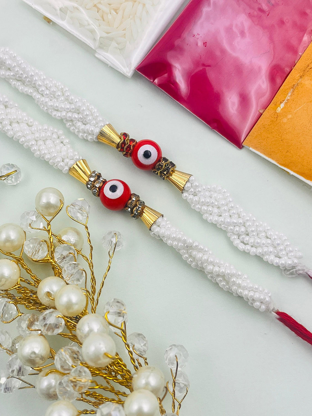 TANAIRA Set Of 2 Pearls Beaded Evil Eye Rakhis Comes With Roli Chawal Tilak