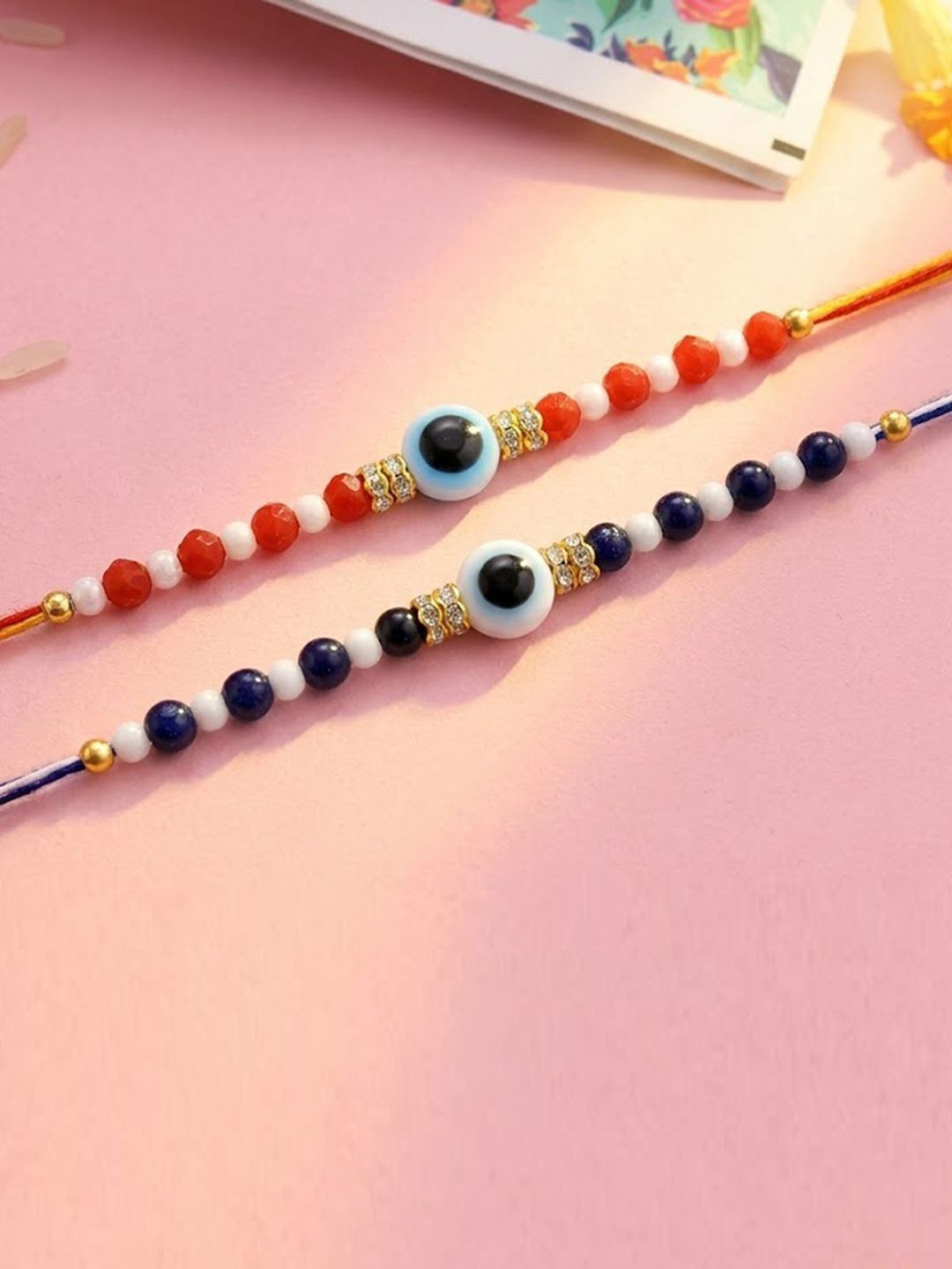 Peora Set Of 2 Gold-Toned Evil Eye Beaded Rakhi With Orange & Blue Thread