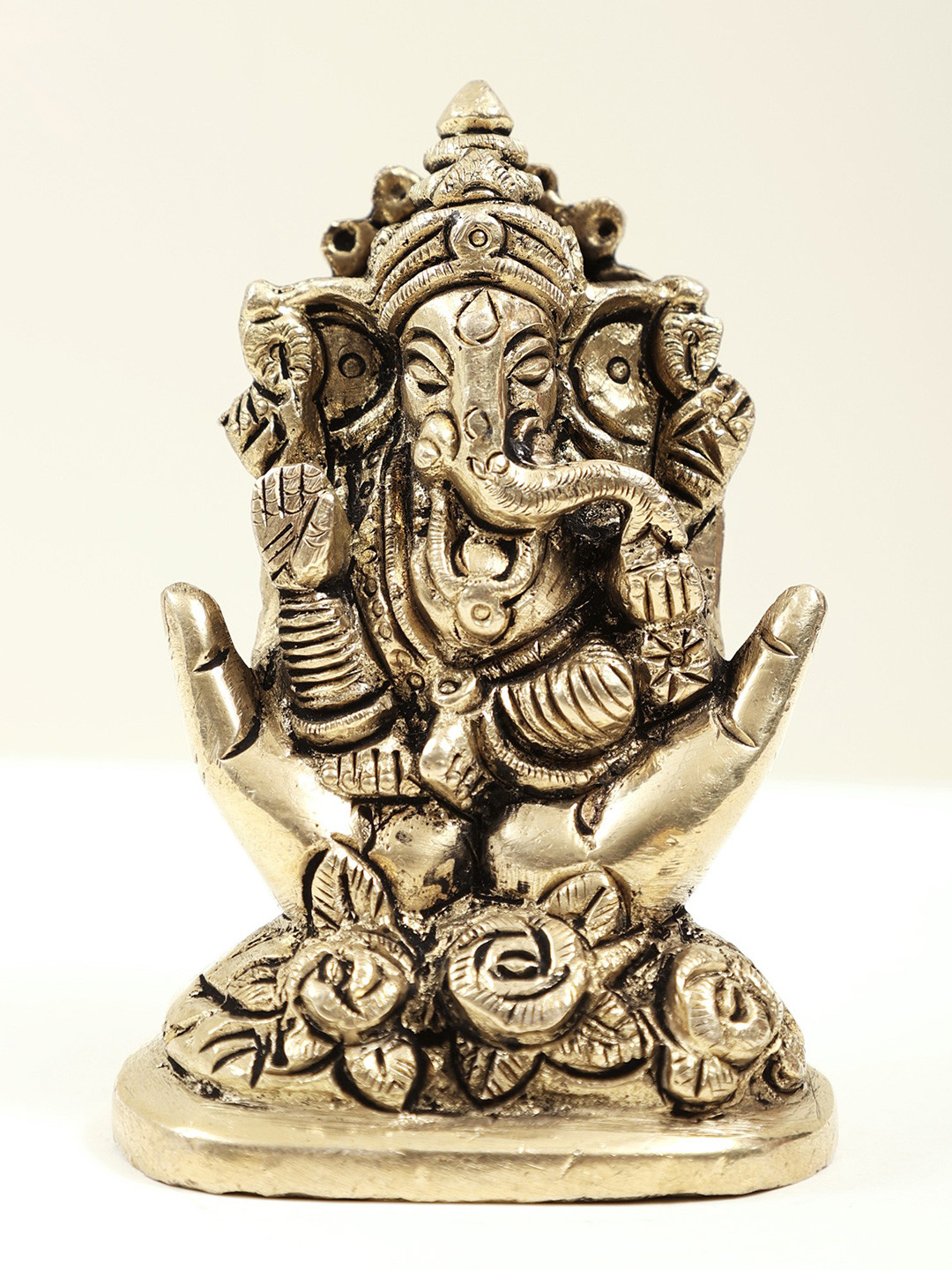 Exotic India Gold-Toned Ganesha Seated on Hand Shaped Pedestal Showpiece