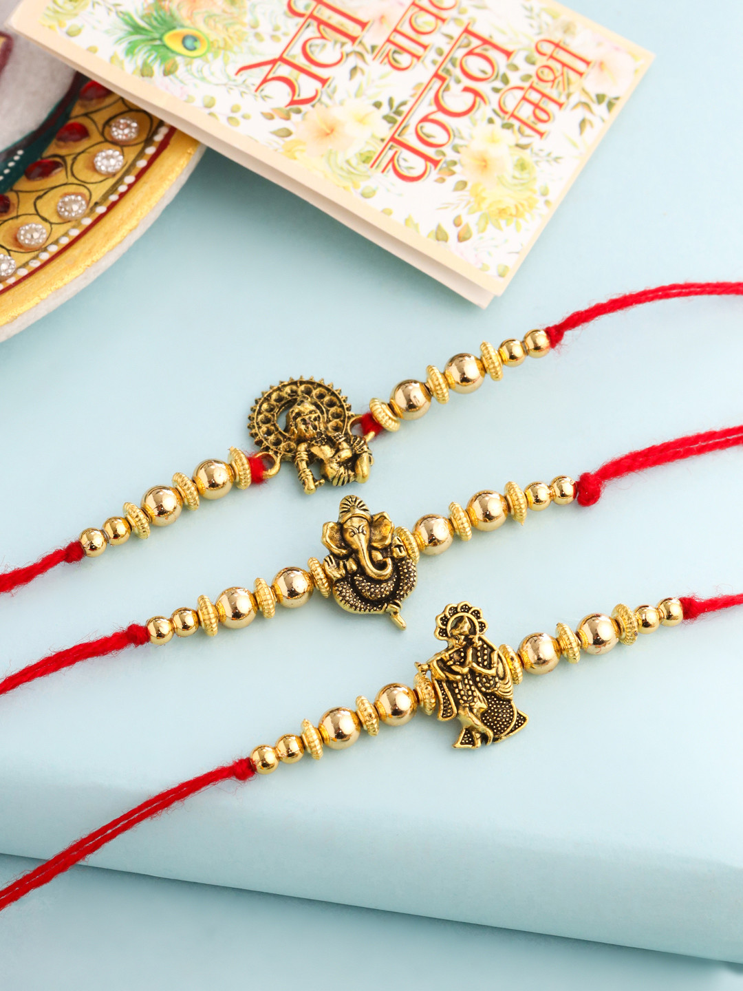 NVR Unisex Set of 3 Gold Toned er Ganesh Ji Thread Rakhi with Roli Chawal Chandan Mishri