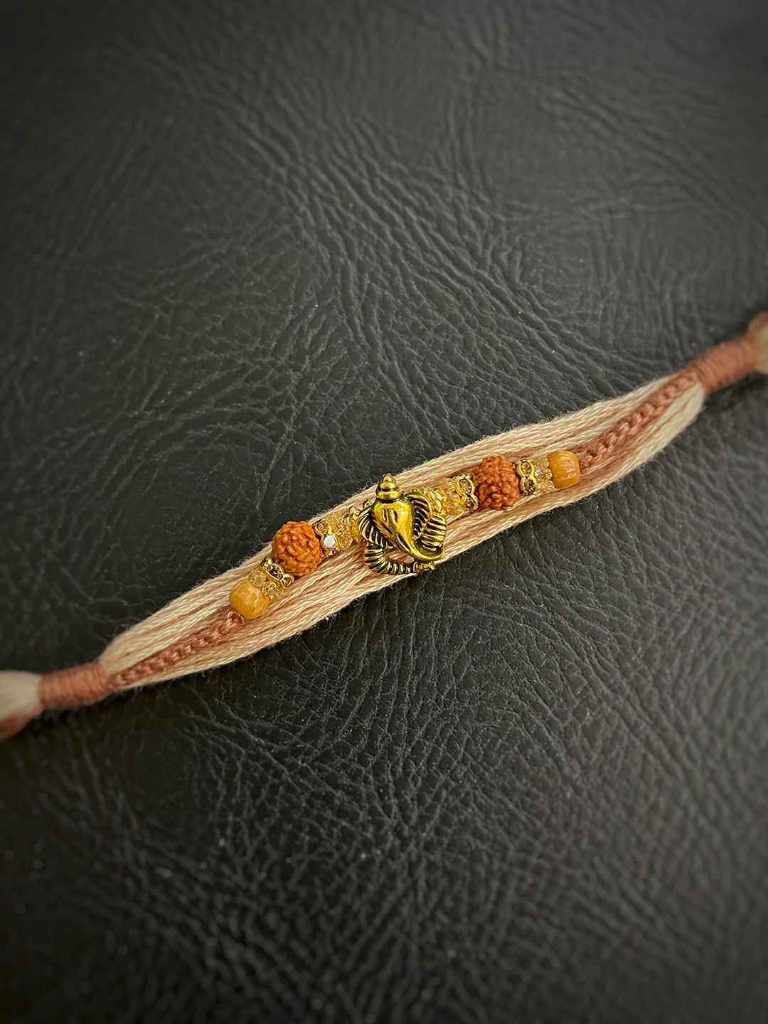 

Digital Dress Room Cream & Orange Ganesh Ji Pendant Rudhraksha Mauli Rakhis