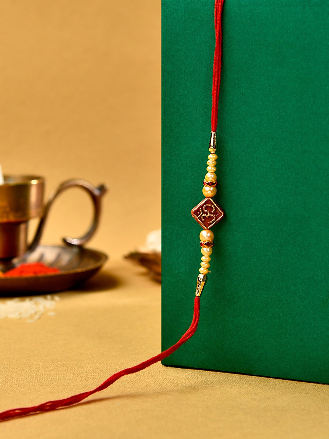 

Zaveri Pearls Men Red Om Beaded Rakhi With Chawal Roli