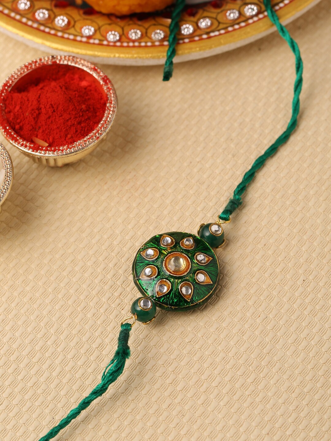 

Tistabene Green Stone Studded Floral Enamelled Rakhi