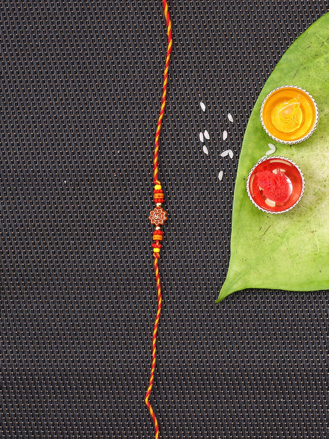 

Aapno Rajasthan Red & Yellow Traditional Swastik Motif Mauli Rakhi