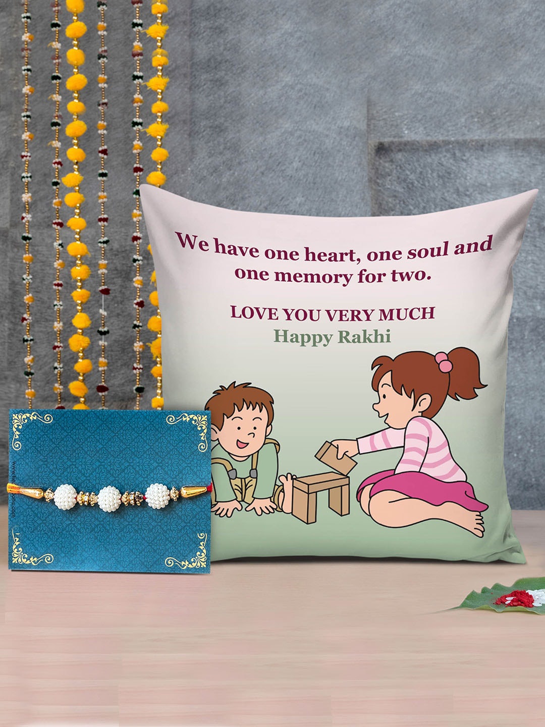 

TIED RIBBONS Multicoloured Designer Rakhis with Printed Cushion & Roli Chawal Combo Pack, Multi