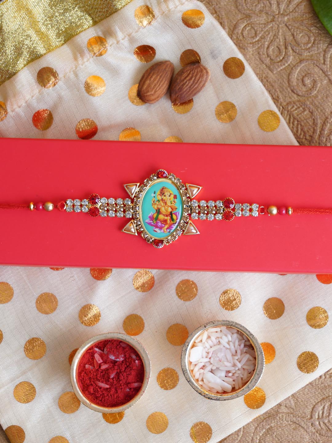 

TIED RIBBONS Red & Gold-Toned Designer Stone-Studded Ganesha Rakhi with Card & Roli Chawal