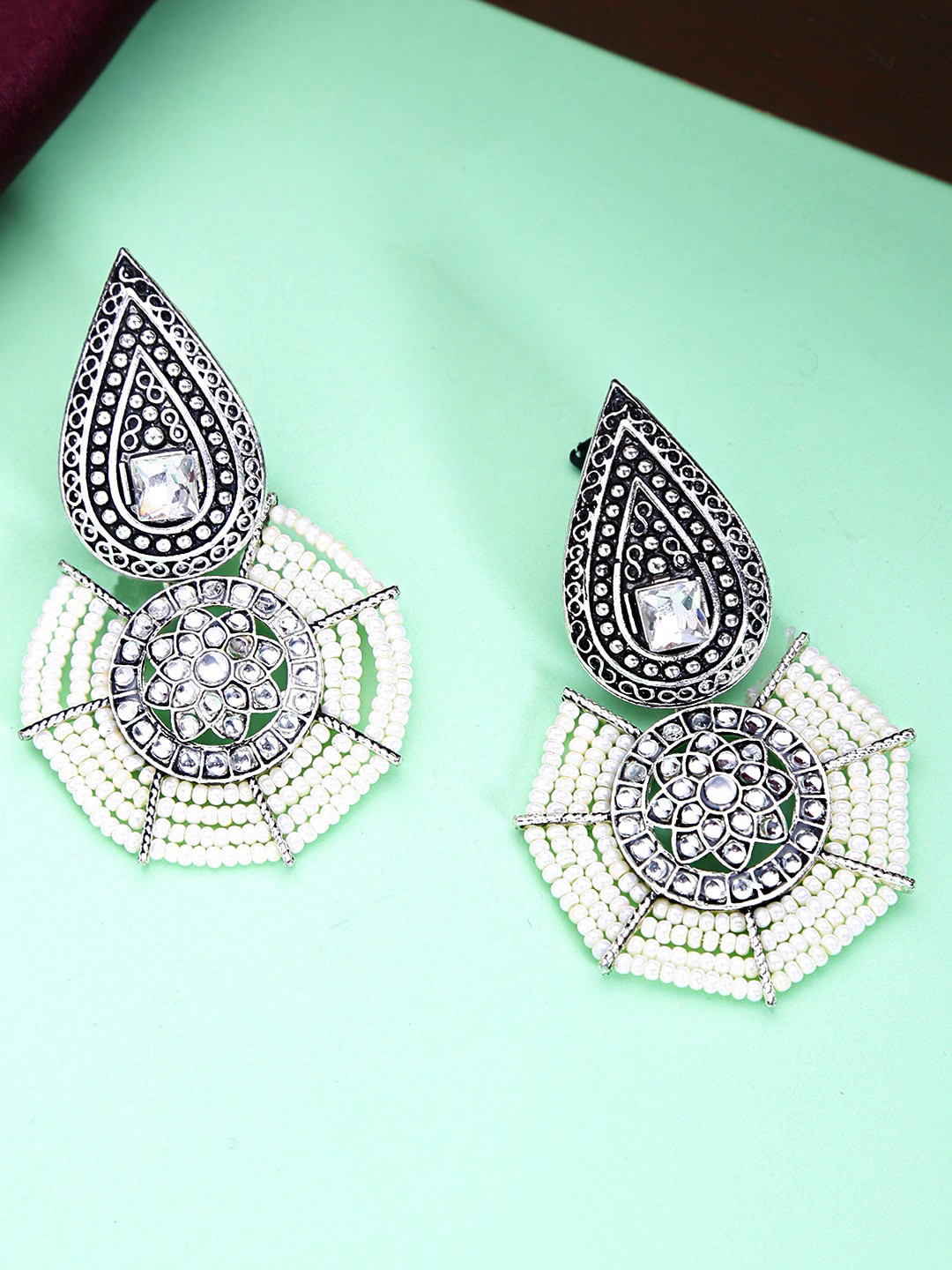 

Yellow Chimes White & Silver-Toned Teardrop Shaped Oxidised Drop Earrings