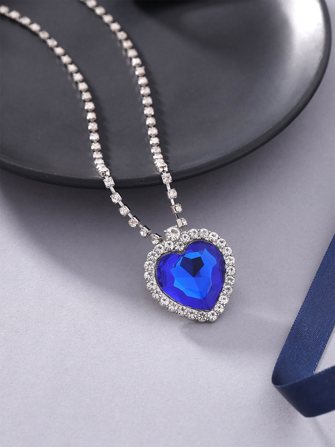 

Yellow Chimes Rhodium-Plated Blue & White Crystal-Studded Heart Shaped Pendant With Chain