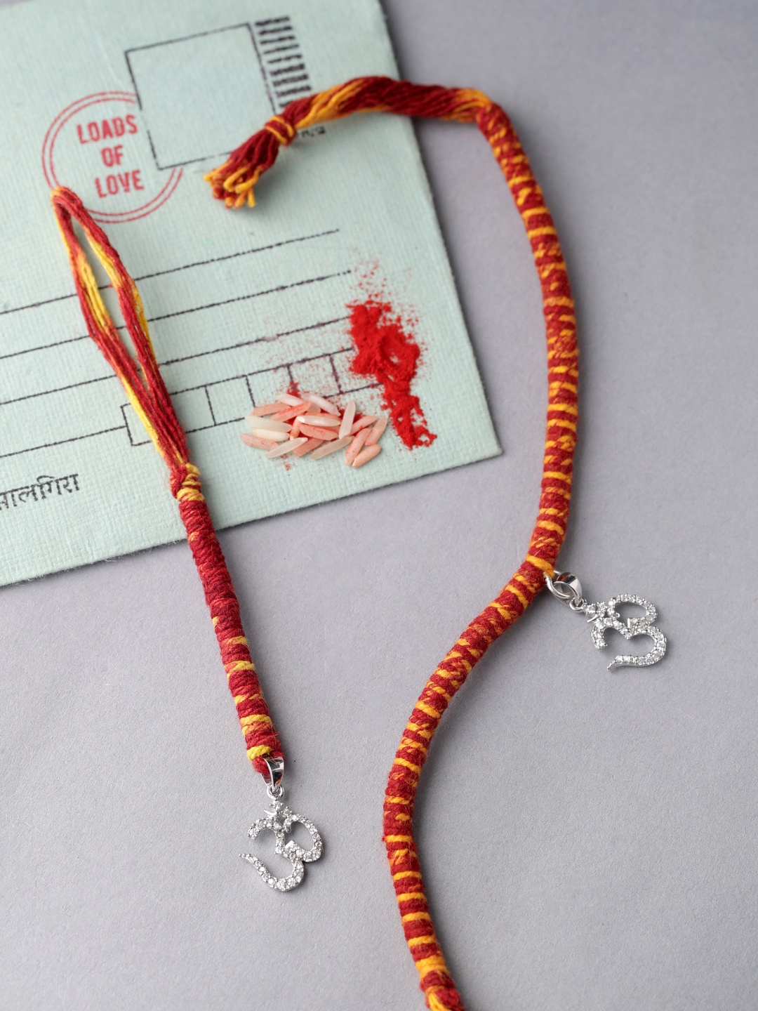 

ADORN by Nikita Ladiwala Silver-Toned & Red Rakhi With Roli Chawal & Greeting Card