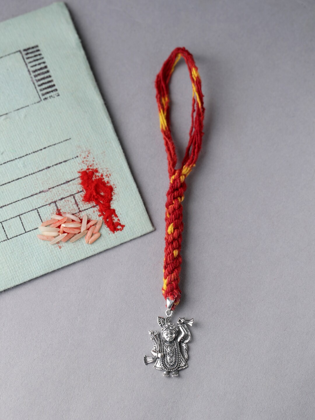 

ADORN by Nikita Ladiwala Silver-Toned & Red Rakhi With Roli Chawal