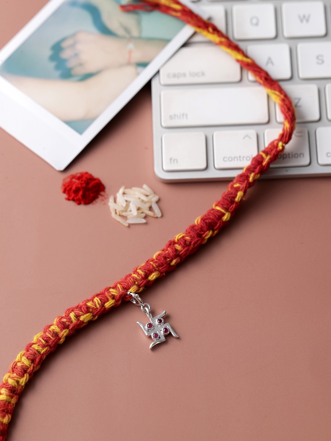 

ADORN by Nikita Ladiwala Silver-Toned & Red Swastik Charm Rakhi With Roli Chawal