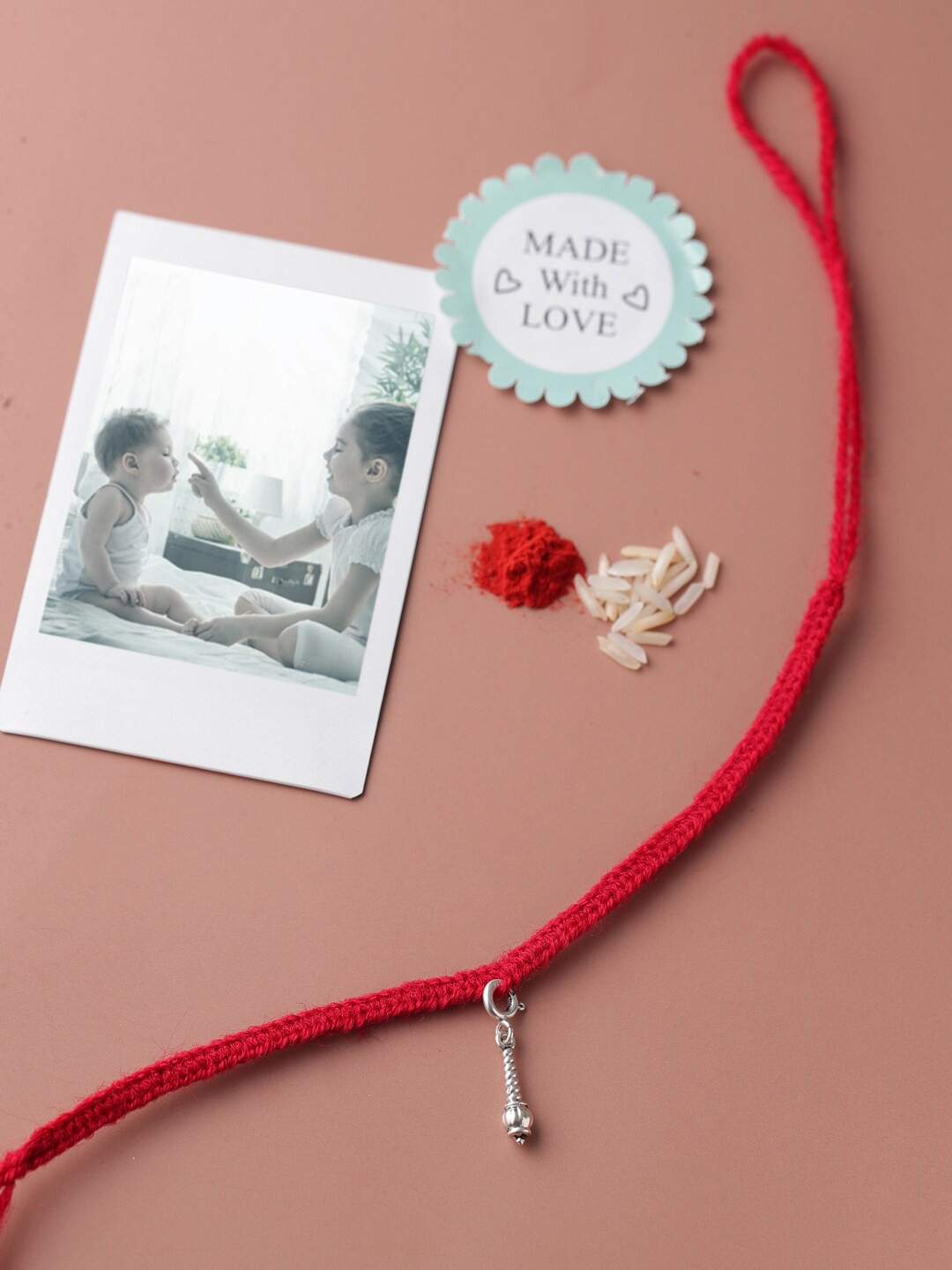 

ADORN by Nikita Ladiwala Silver-Toned & Red Rakhi With Roli and Chawal