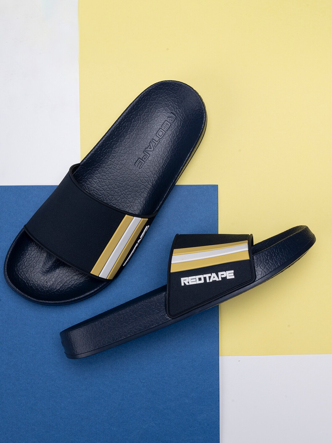 

Red Tape Men Navy Blue & Mustard Striped Rubber Sliders