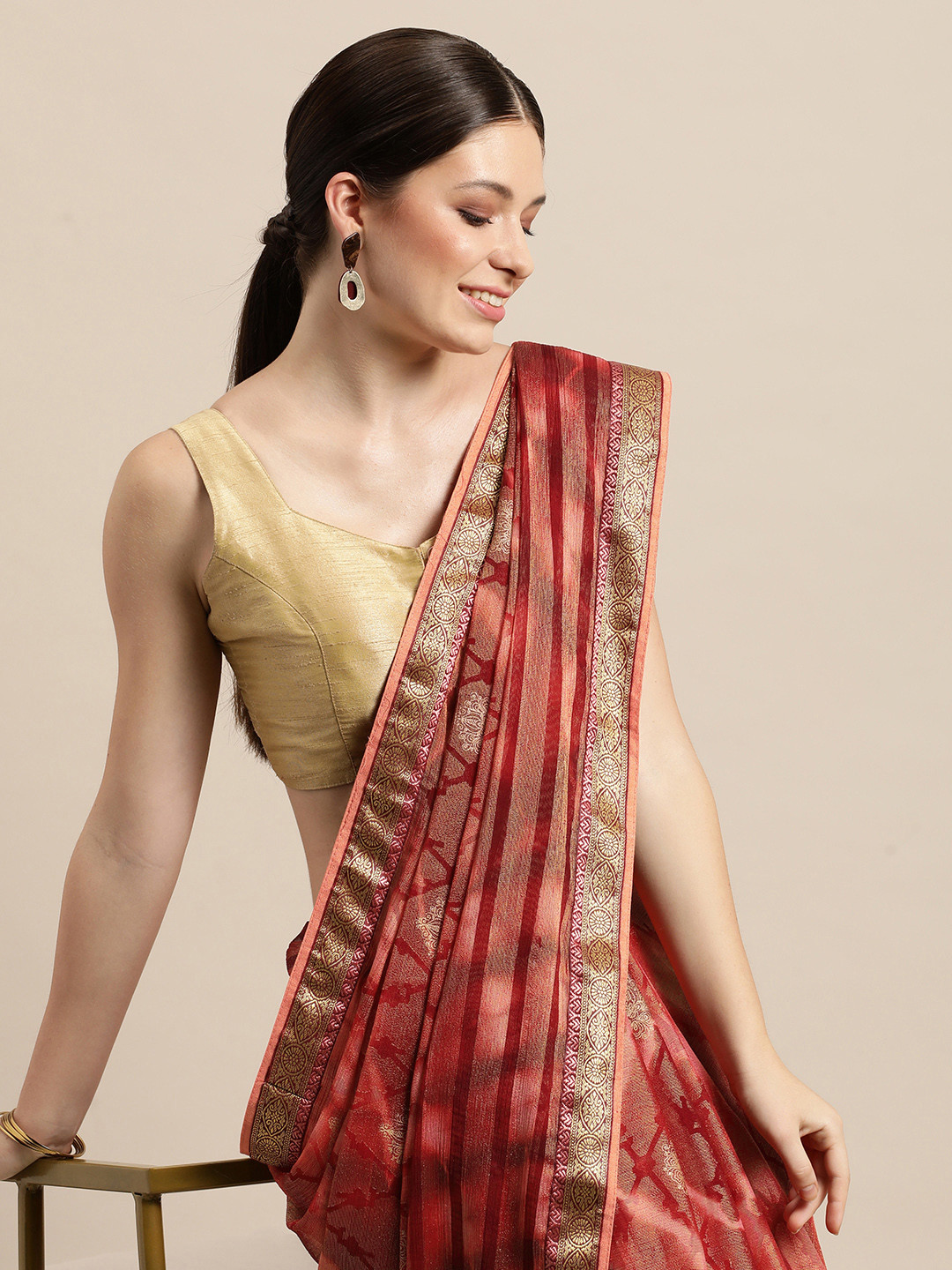 

Triveni Red & Golden Ethnic Motifs Printed Brasso Saree