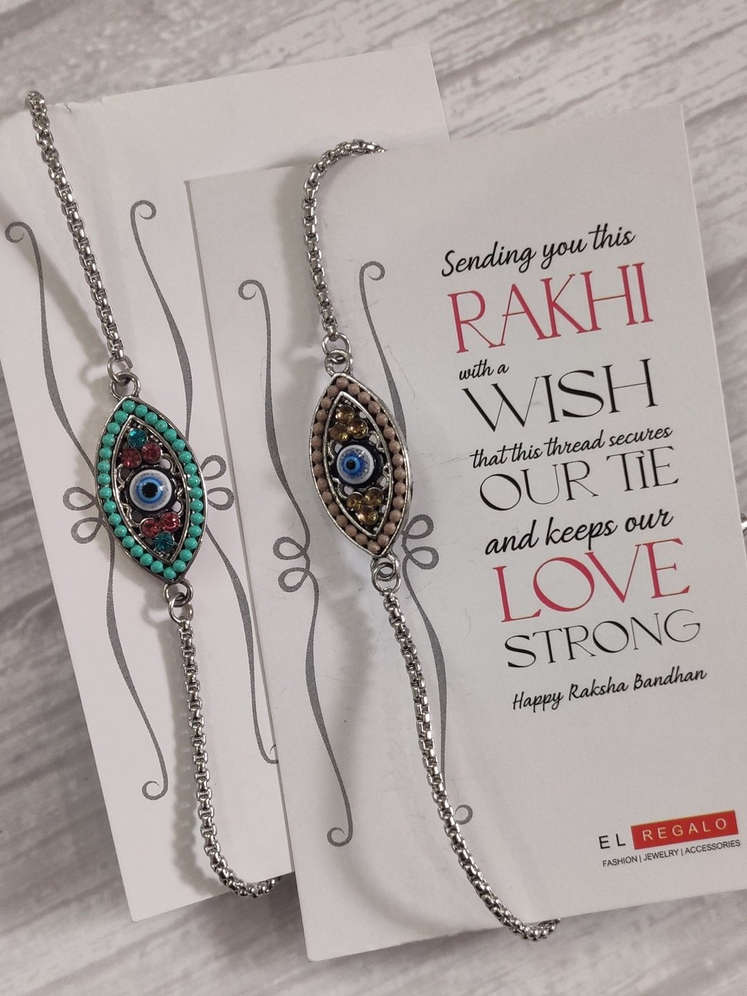 

EL REGALO Bhaiya Bhabhi Set Of 2 Evil Eye-Charm Rakhi With Roli Chawal & Greeting Card, Silver