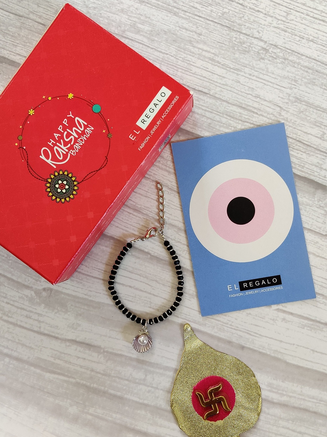 

EL REGALO Kids Gold-Toned Nazaria Rakhi Combo with Greeting Card & Roli Chawal Shagun