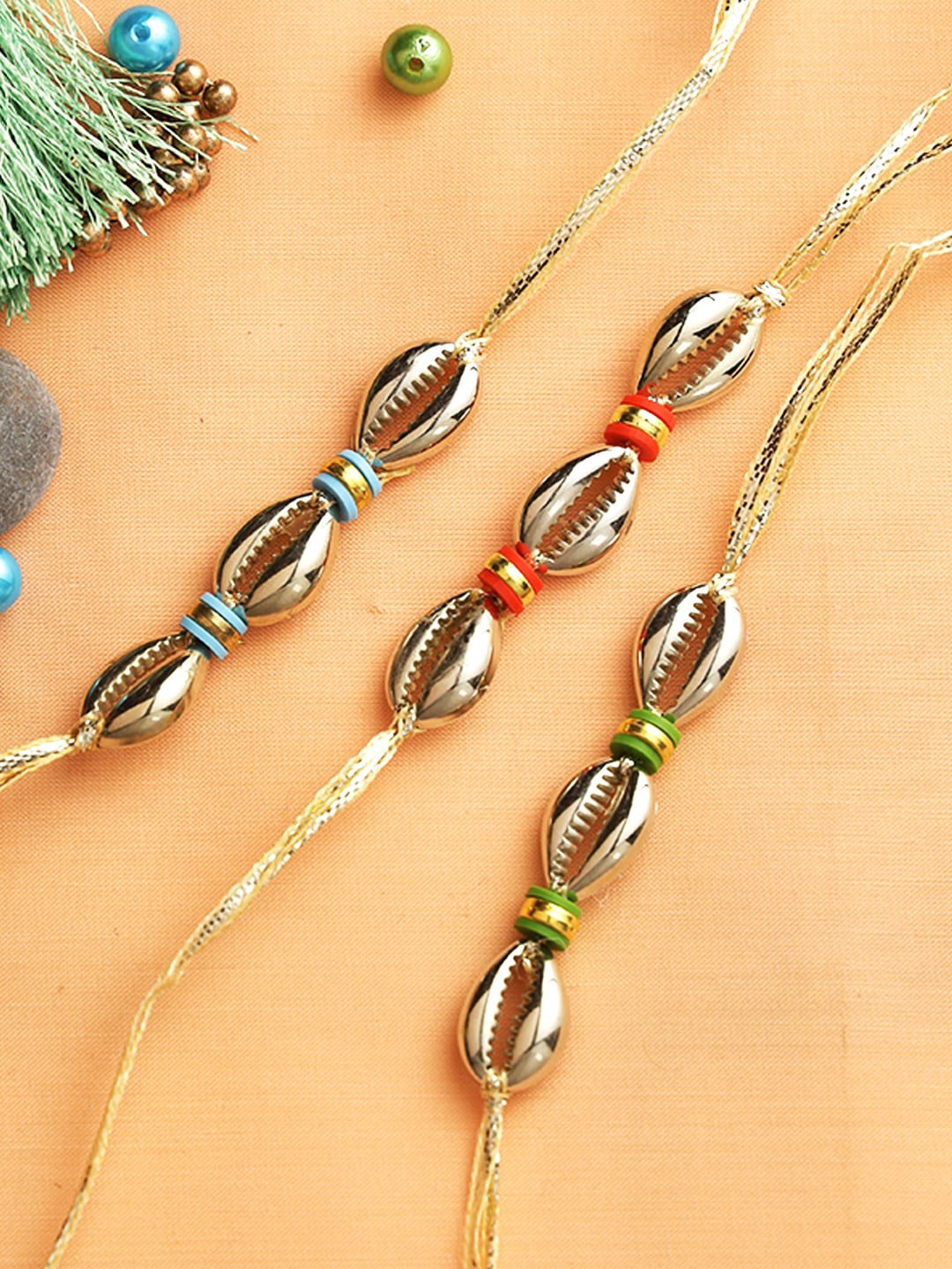 

Aapno Rajasthan Set of 3 Golden Shell Beaded Rakhi with Roli Chawal & Greetings Card, Multi