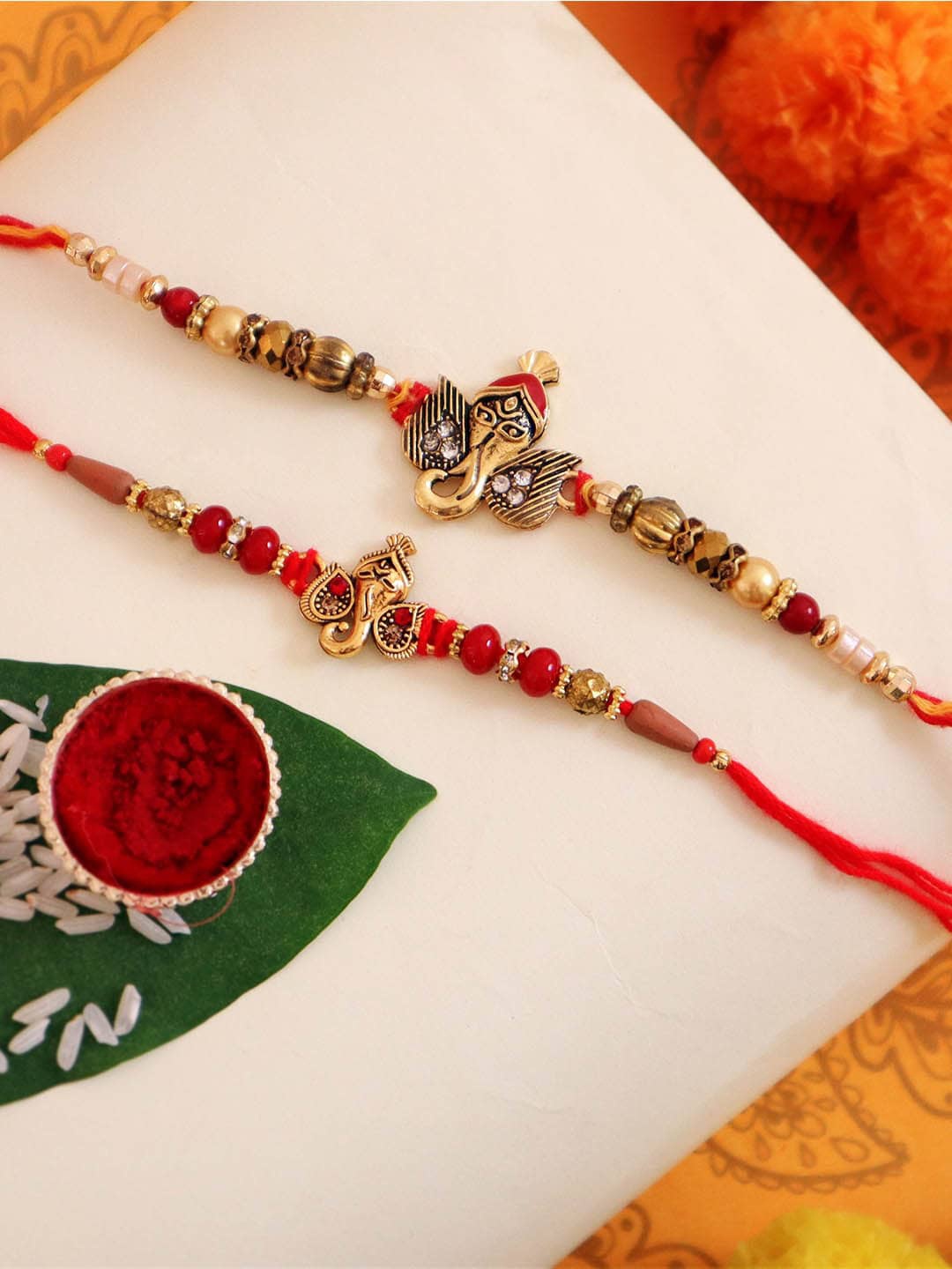 

TIED RIBBONS Set of 2 Designer Ganesha Rakhi with Card & Roli Chawal Gift Pack, Red
