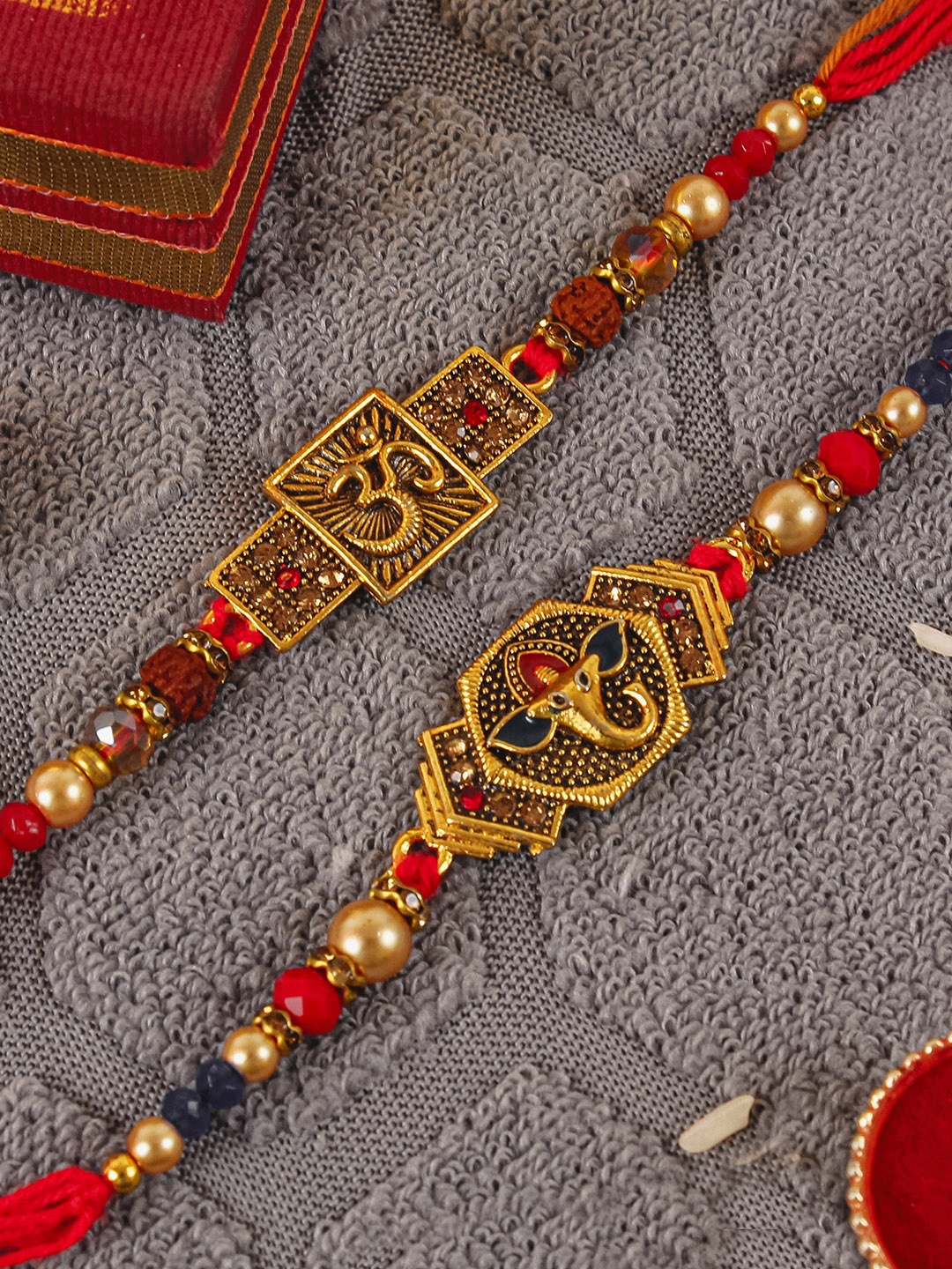 

TIED RIBBONS Set of 2 Stoned-Studded Om & Ganesha Rakhi with Card & Roli Chawal, Multi