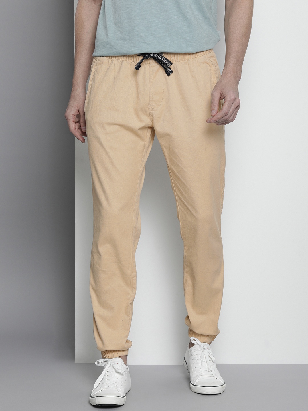 

Tommy Hilfiger Men Beige Solid Slim Fit Trousers with Drawstring Closure