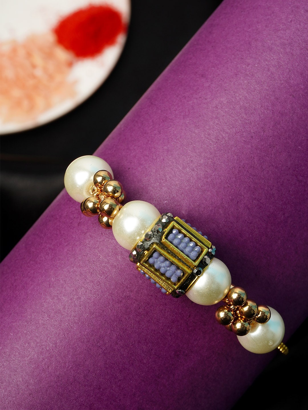 

Urmika White & Lavender Pearl Rakhi With Roli Chawal