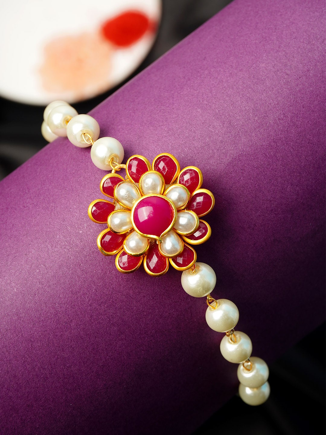 

Urmika Fuchsia Pink & White Floral Pearl Rakhi With Roli Chawal