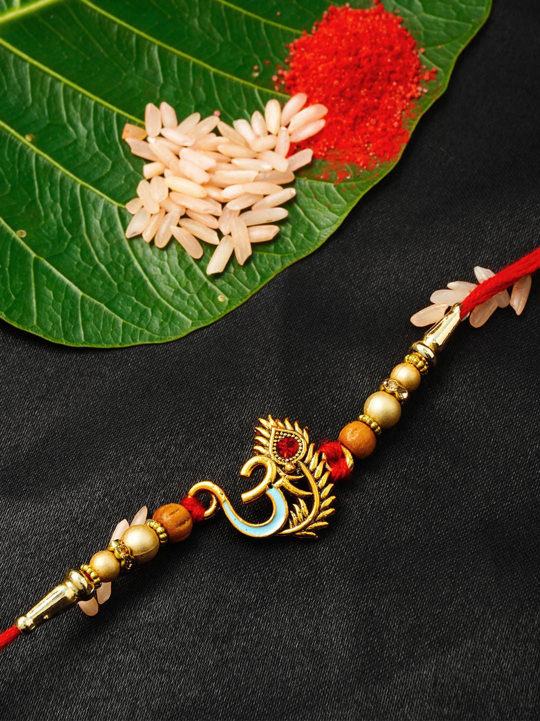 

Urmika Golden & Red Om with Mor Pankh Rakhi With Roli Chawal, Gold