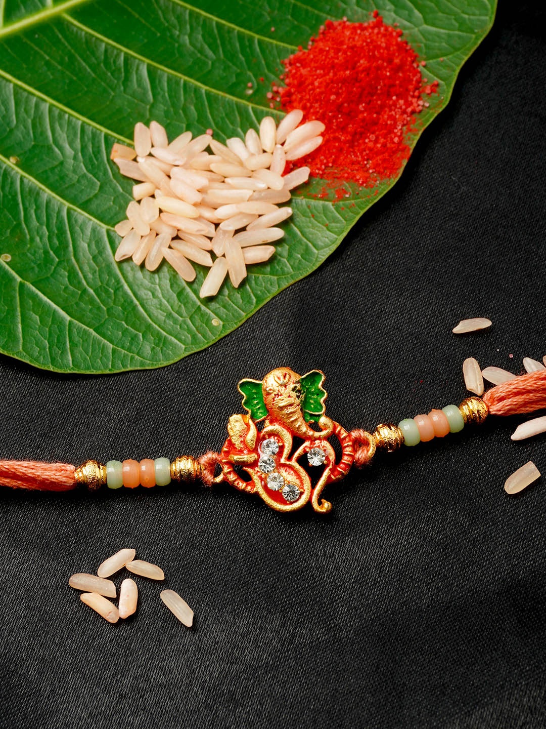 

Urmika Men Gold-Toned & Peach-Colored Stone-Studded & Beaded Shri Ganesh Om-Charm Rakhi With Roli Chawal