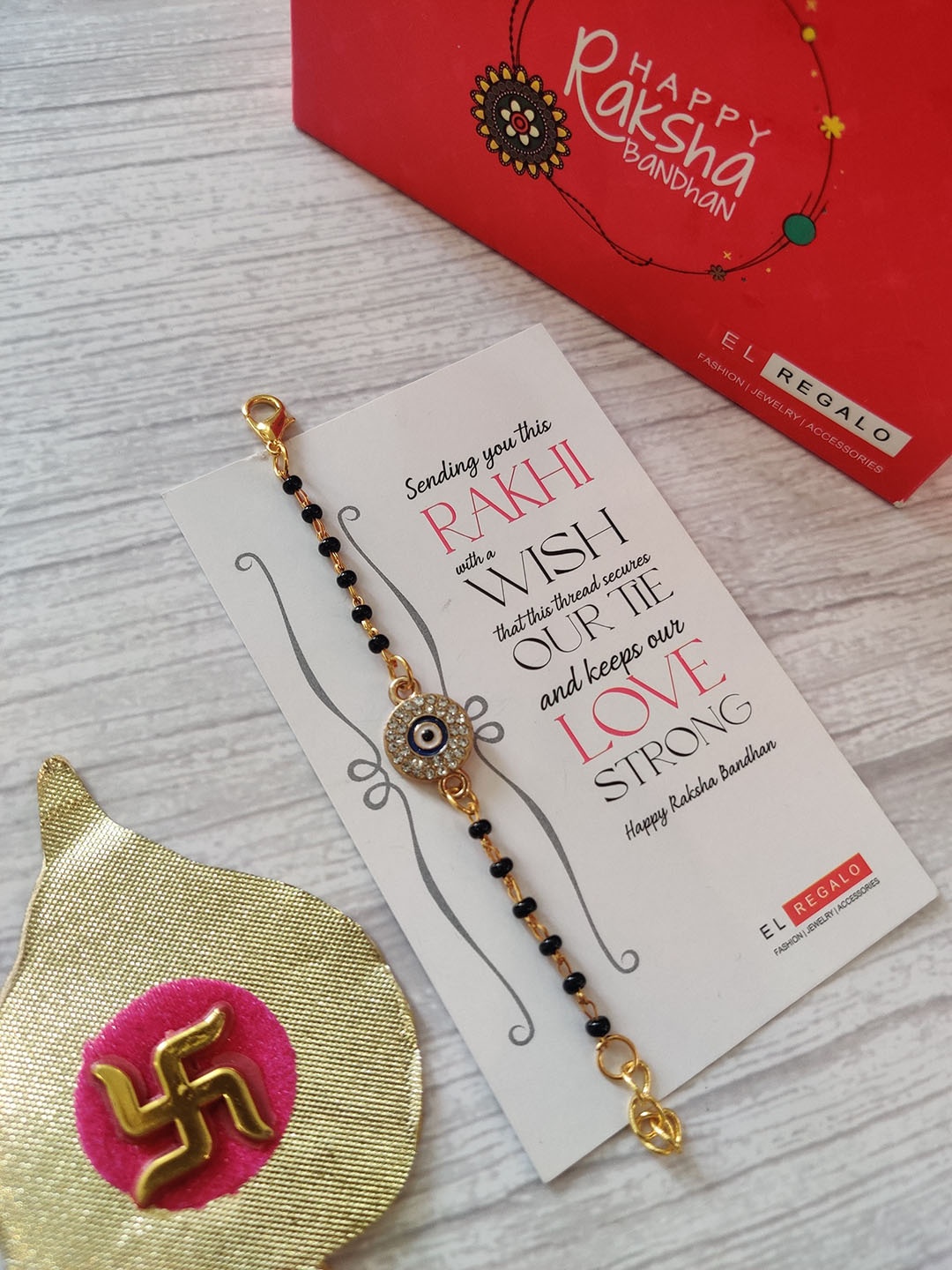 

EL REGALO Kids Gold-Toned Nazaria Rakhi Combo with Greeting Card & Roli Chawal Shagun