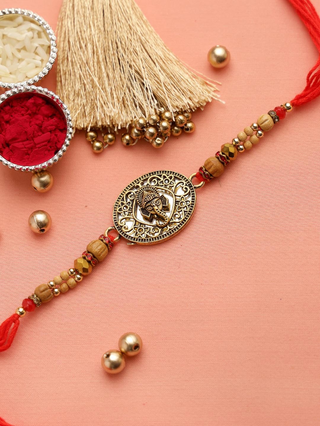 

Aapno Rajasthan Gold & Red Lovely Wooden Beads Filigree Work Ganapati Rakhi & Roli Chawal