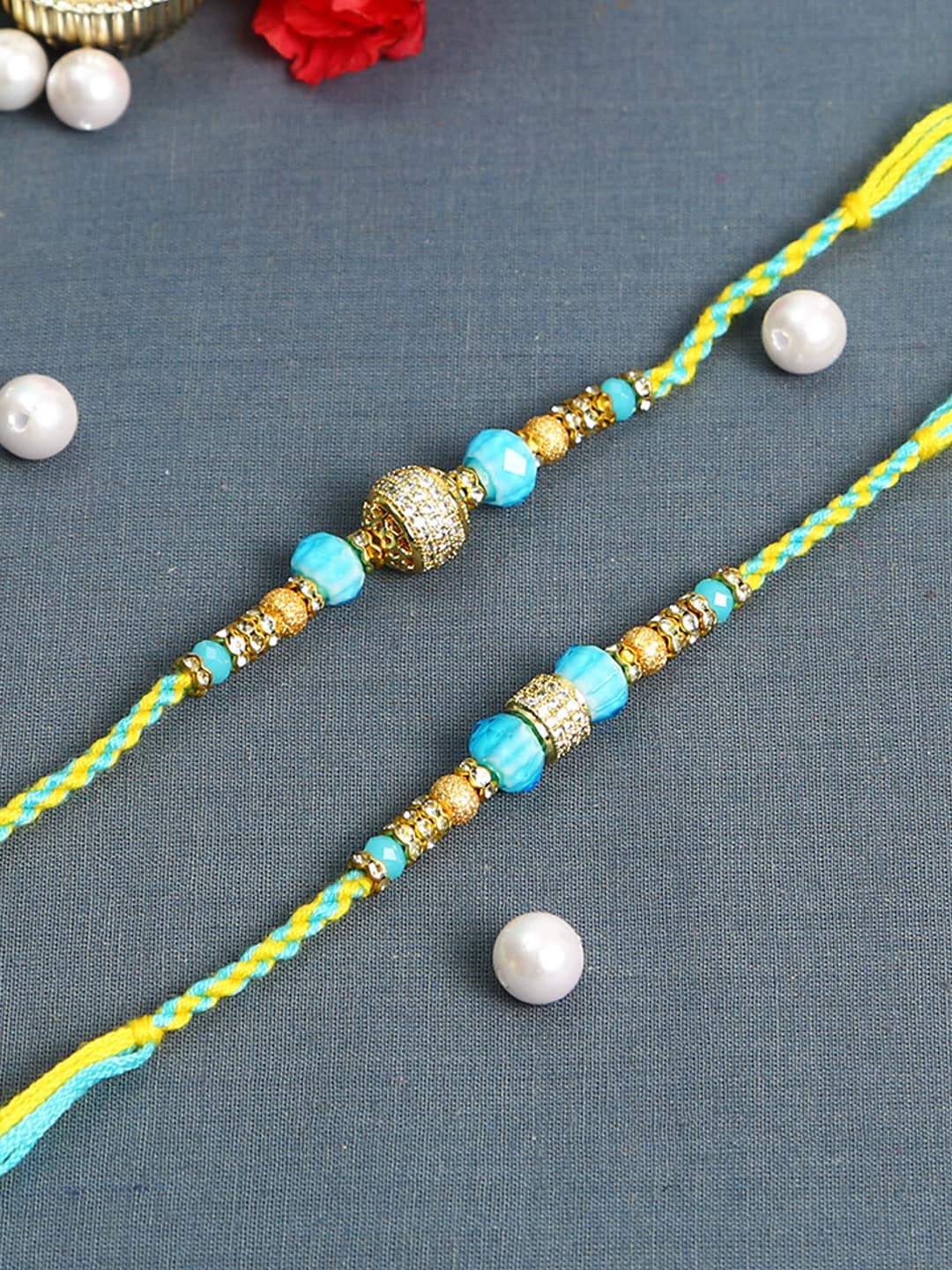

Aapno Rajasthan Set Of 2 Blue & Golden Pearl Studded Rakhi With Roli Chawal, Green