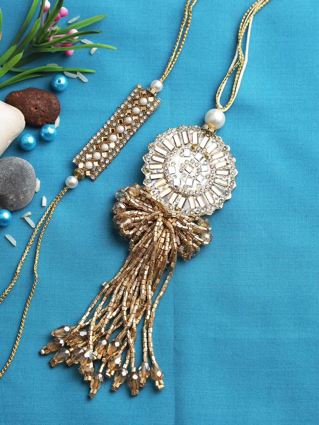 

Aapno Rajasthan Set Of 2 Gold-Toned & White Stone-Studded Rakhi & Lumba With Roli Chawal & Gift Box