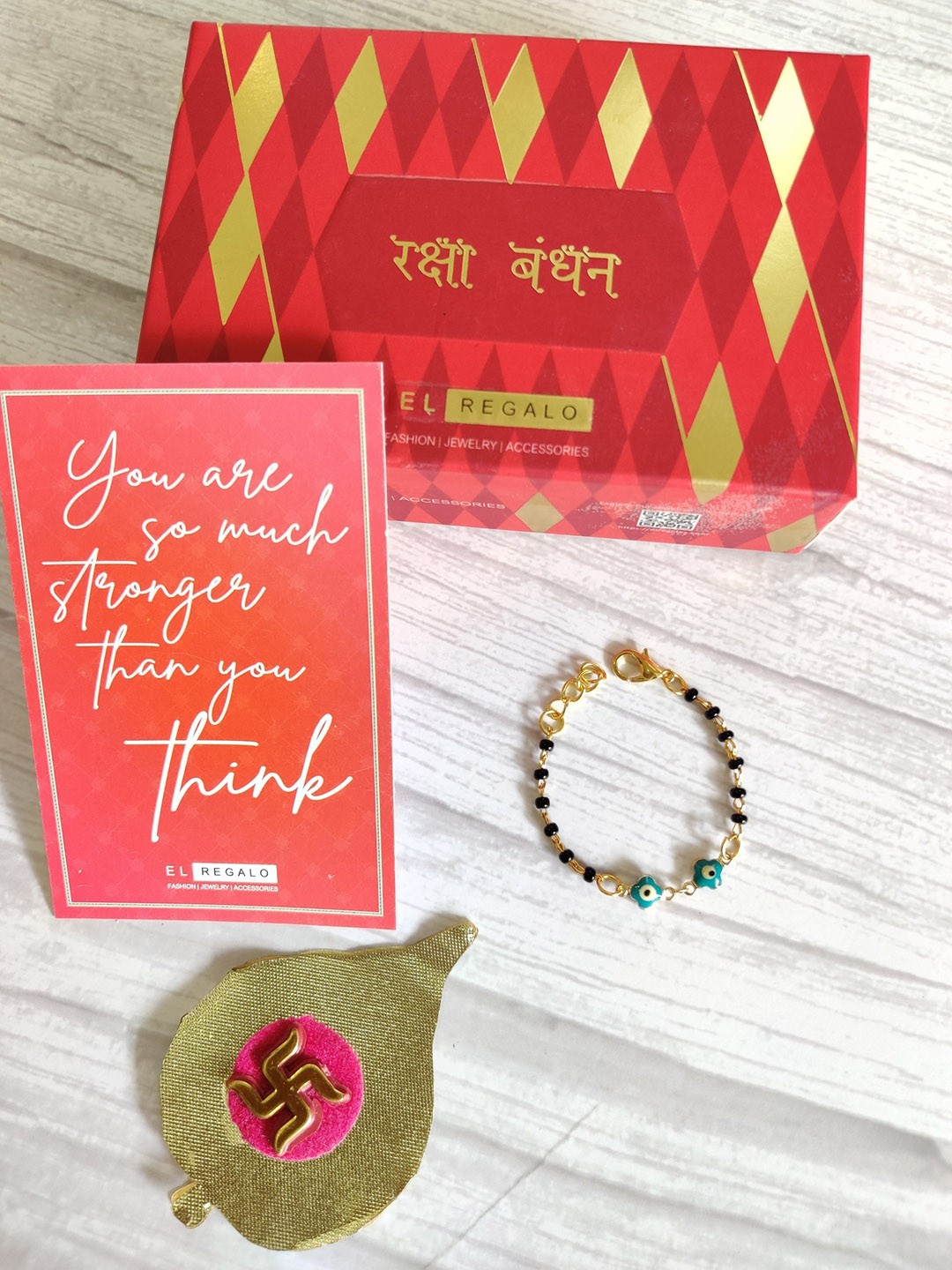 

EL REGALO Baby Gold-Toned Nazaria Rakhi Combo With Greeting Card & Roli Chawal Shagun