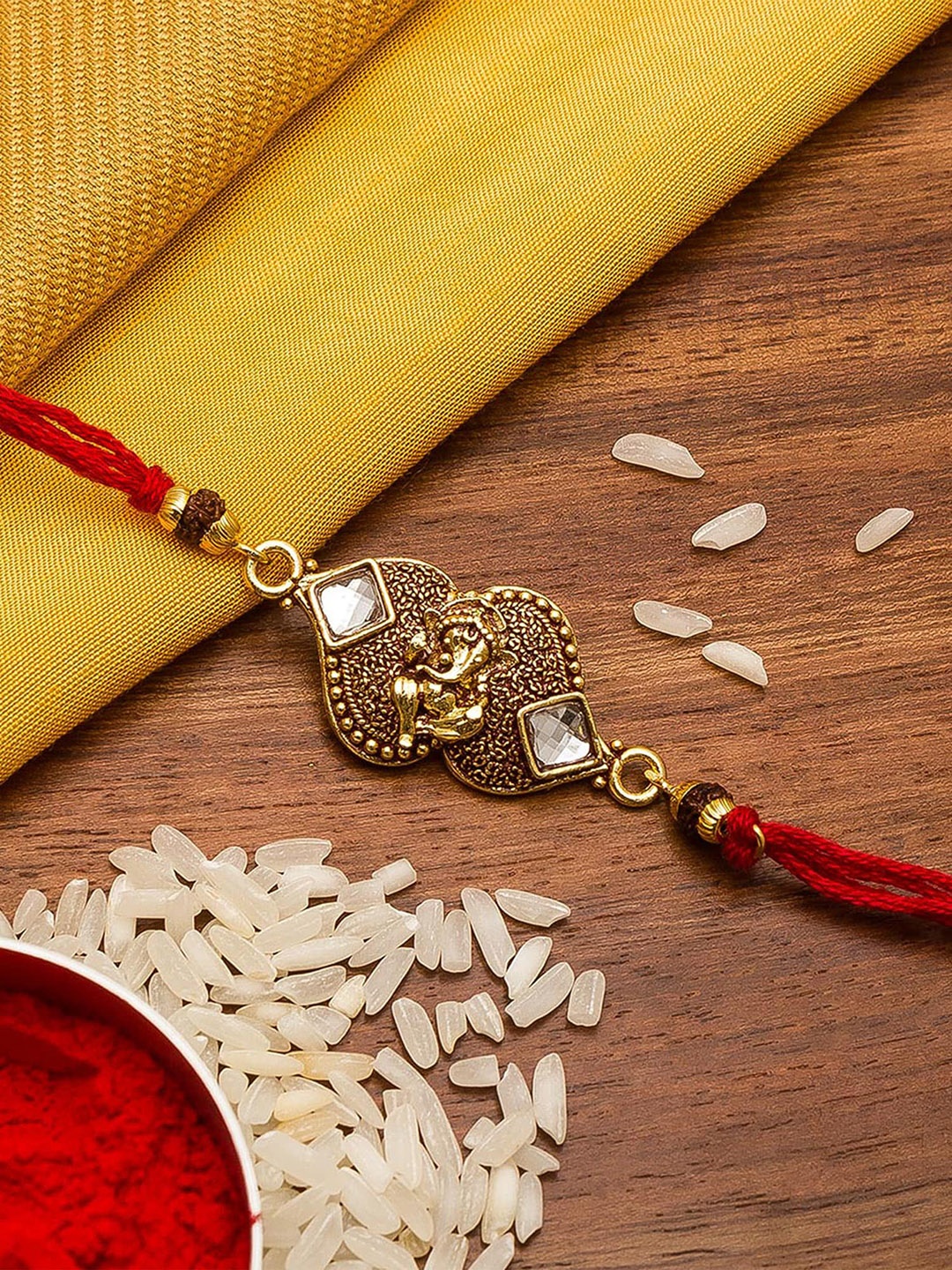 

Aadita Men Gold-Toned Stone Studded Lord Ganesha Rakhi With Roli Chawal