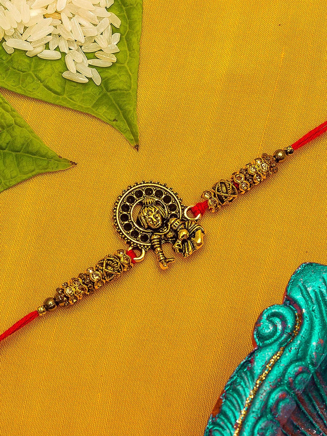 

aadita Gold-Toned & Red Thread Rakhi With Roli Chawal