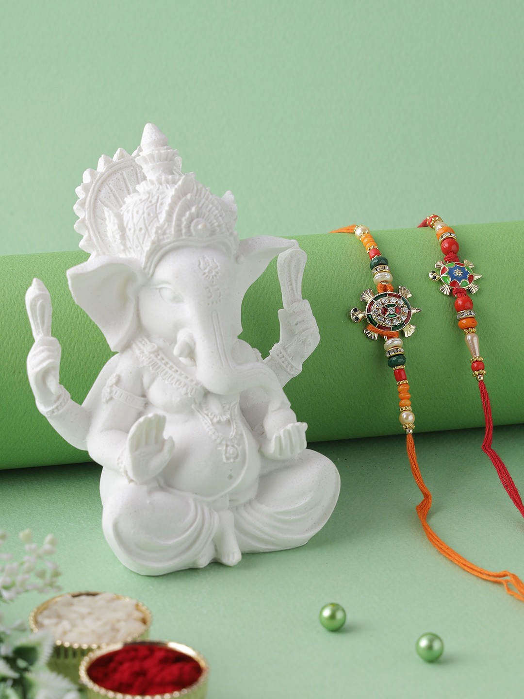 

Aapno Rajasthan Multicoloured Set of 2 Rakhi with Polyresin Ganesha Idol Gift Set, Multi