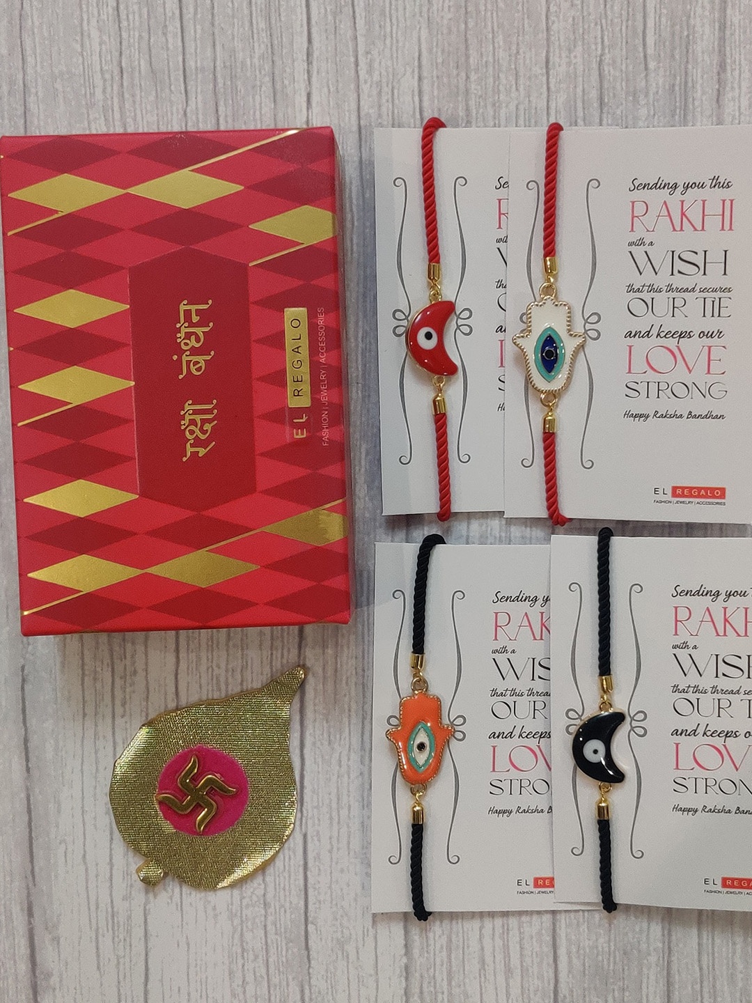 

EL REGALO Set Of 4 Red & Black Evil Eye Wrap Around Rakhi With Roli Chawal & Raksha Bandhan Greeting Card