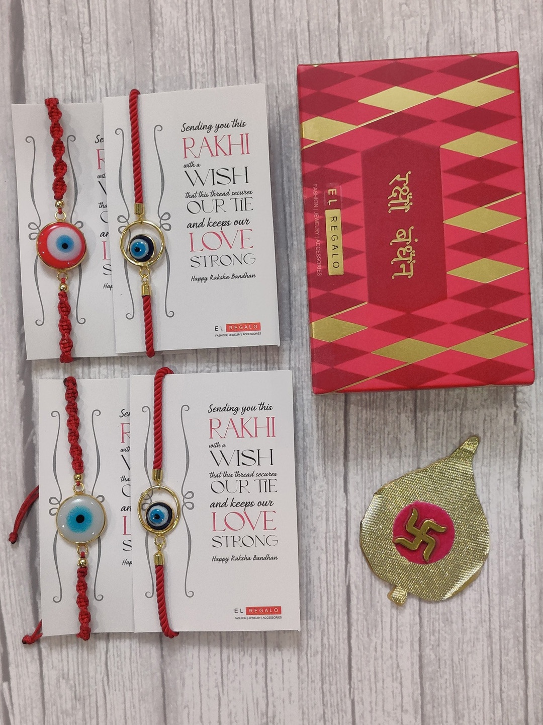 

EL REGALO Set Of 4 Red & Gold Coloured Evil Eye Wrap Around Rakhi With Roli Chawal & Raksha Bandhan Greeting Card